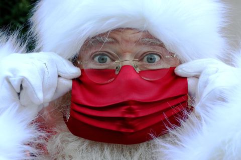 Ein Weihnachtsmann mit weißem Bart und weißer Kapuze trägt eine rote Gesichtsmaske