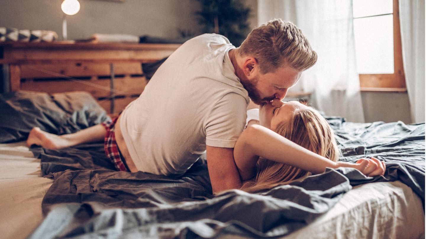 Was Menschen zu einem Seitensprung bewegt: Pärchen küsst sich auf einem Bett