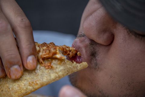 Ein Mann isst eine "Quesadilla" auf der Straße.