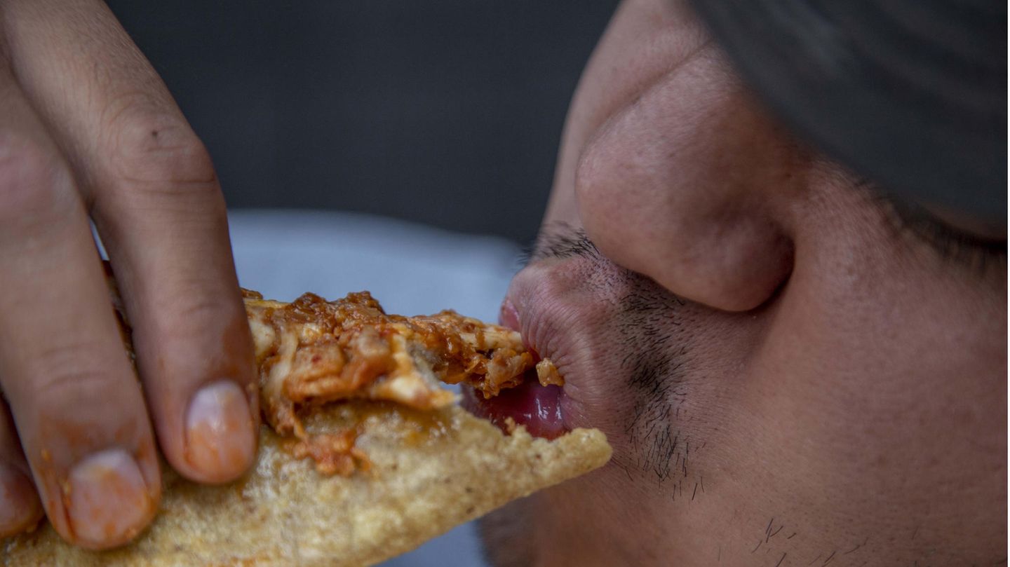 Ein Mann isst eine "Quesadilla" auf der Straße.