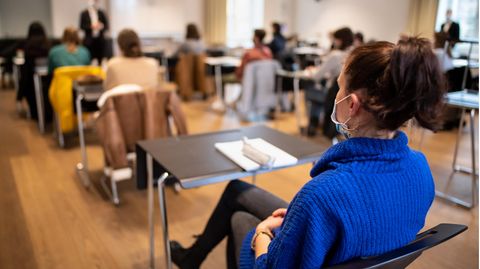 Eine Schülerin sitzt im Unterricht und trägt einen Mund-Nasenschutz