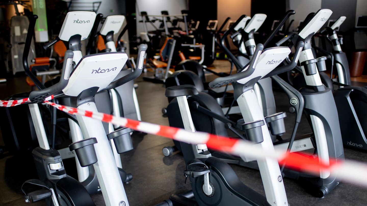 Ein rot-weißes Flatterband ist an Fahrradtrainern befestigt, die in einem Fitnessstudio stehen