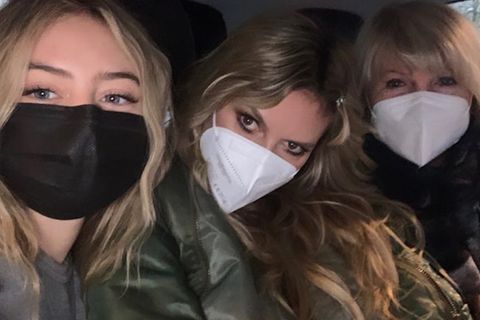 Vor einem dunklen Hintergrund sitzen drei Frauen mit weißen Masken: Leni Klum links, Heidi Klum in der Mitte und Erna rechts