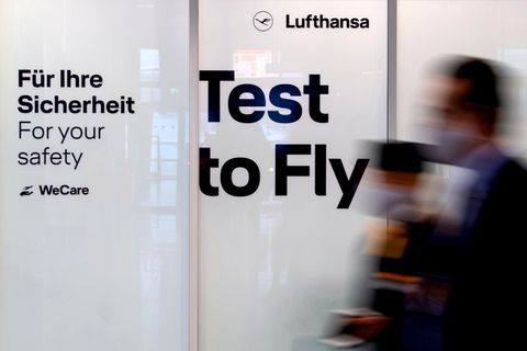 Mitarbeiter von Lufthansa laufen am Flughafen München an einem Covid-19 Testcenter vorbei. 