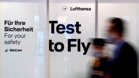 Mitarbeiter von Lufthansa laufen am Flughafen München an einem Covid-19 Testcenter vorbei. 