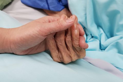 Die Hände einer älteren und einer jüngeren Person berühren sich