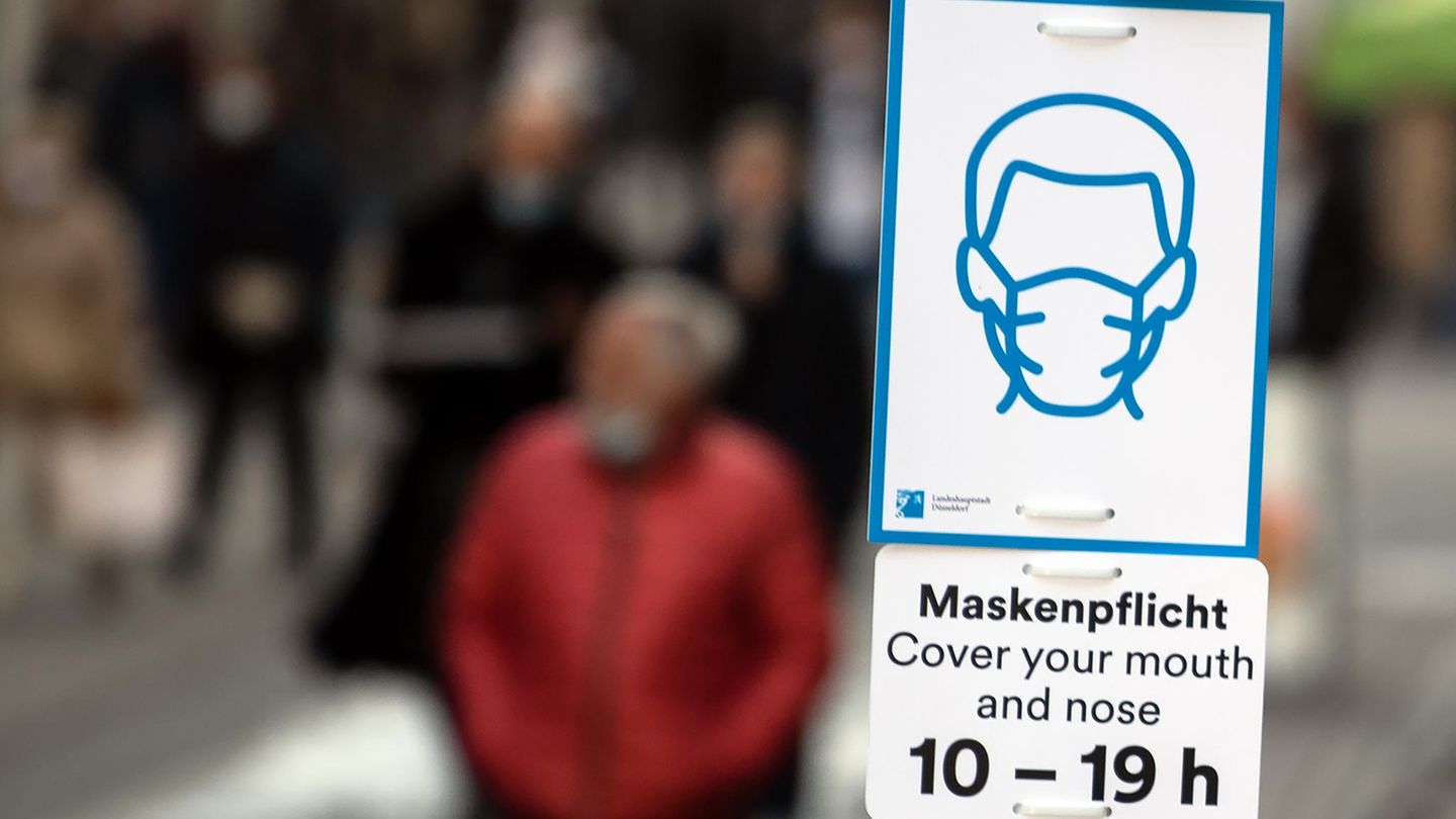 A sign indicates the obligation to Wear protective masks