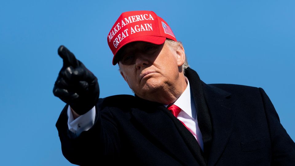 Donald Trump mit roter MAGA-Kappe und schwarzen Handschuhen zeigt in die Kamera