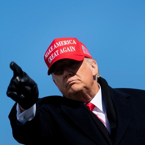 Donald Trump mit roter MAGA-Kappe und schwarzen Handschuhen zeigt in die Kamera