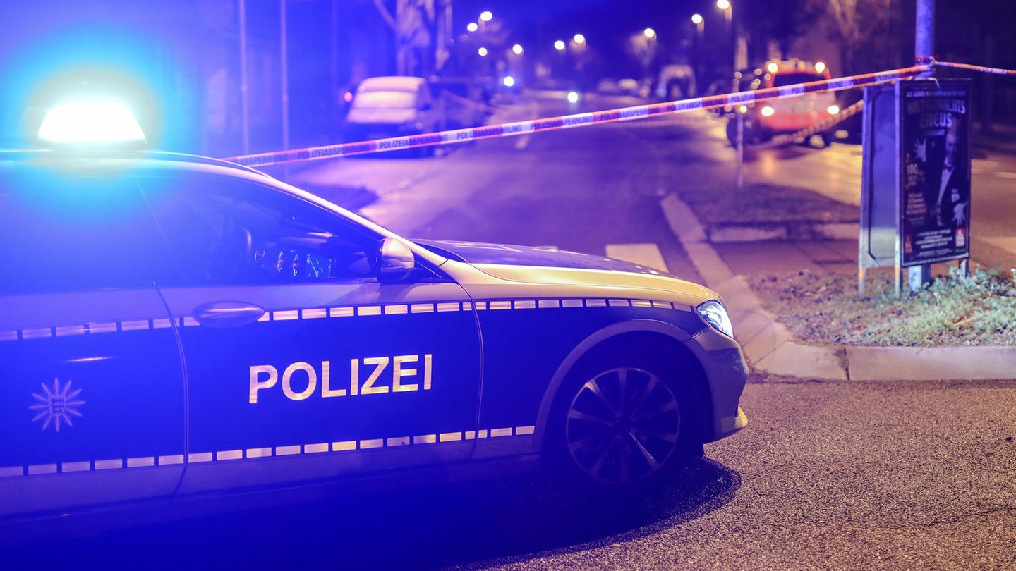 Mann attackiert Polizisten mit Messer und Dachziegeln: Polizeiwagen mit Blaulicht vor Absperrband