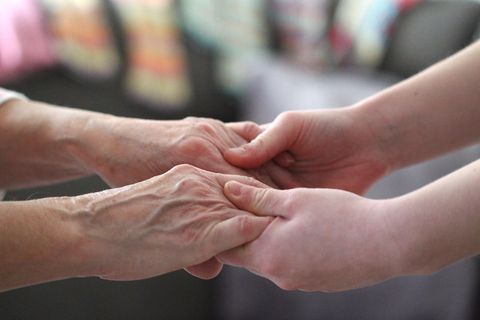Eine alte Frau hält die Hände einer jungen Frau