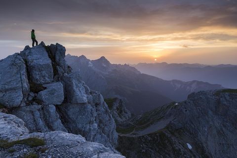 Person steht auf Berg uns schaut in den Himmel