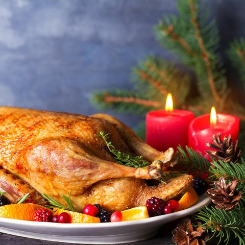 Ganze gebratene Ente mit Orangen, Beeren und Kräutern und Weihnachtsdekorationen