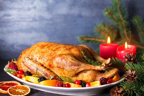 Ganze gebratene Ente mit Orangen, Beeren und Kräutern und Weihnachtsdekorationen