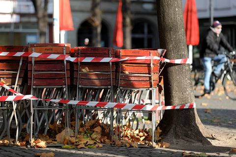 Ein Radfahrer fährt an zusammengestellten Stühlen von Gastronomiebetrieben vorbei