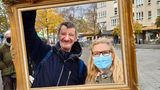 Micha und Ines Sydow posieren mit Bilderrahmen am Franz-Naumann-Platz. Gleich nebenan, in der Residenzstraße 109 befindet sich die Eventgaststätte „Kastanienwäldchen“ von Norbert Raeder. Der sozial engagierte Gastronom nimmt dort werktags ab 16 Uhr Kleiderspenden für Bedürftige entgegen