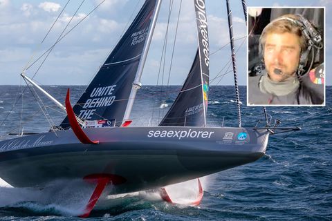 Eine Segelyacht rast auf Foils über das mehr. Rechts oben ist der Kopf eines blonden Mannes zu sehen