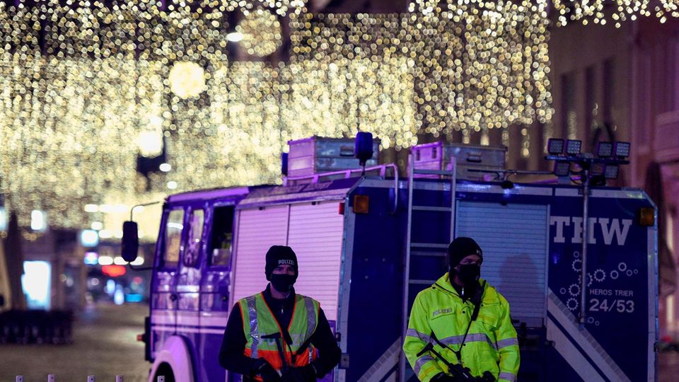 Zwei Polizisten und THW-Lkw vor der weihnachtlich geschmückten Altstadt von Trier
