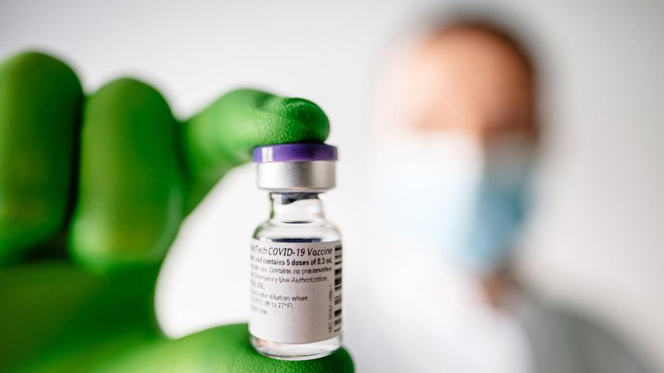 Ein Mitarbeiter des Mainzer Unternehmens Biontech hält ein Fläschen mit Corona-Impfstoff in der Hand