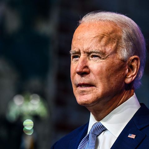 Joe Biden - ein älterer Mann mit weißen, zurückgekämmten Haaren – steht im blauen Anzug vor einem verschwommenen Hintergrund