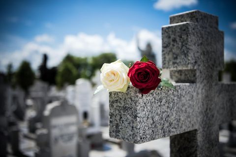 Friedhofskreuz mit einer weißen und einer roten Rose darauf