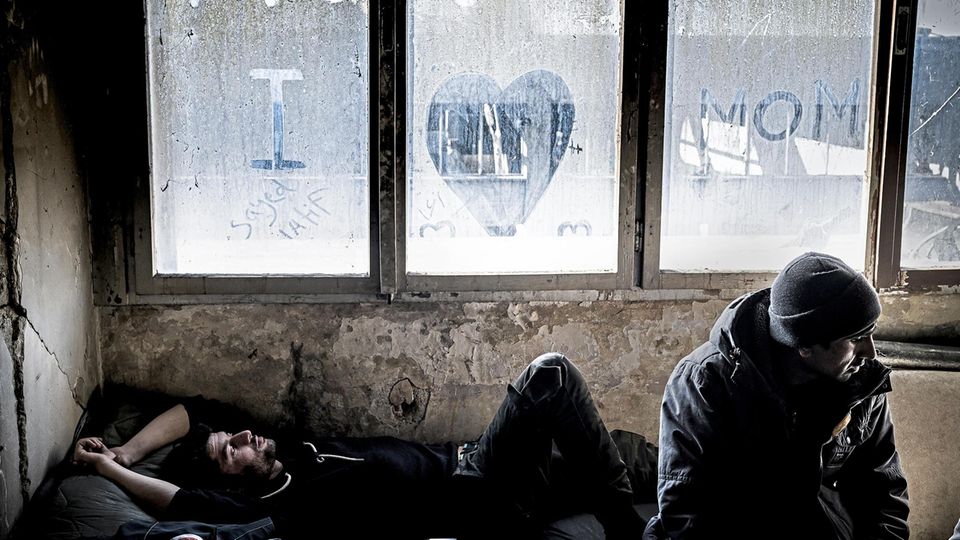 Sayeed Latif, a refugee from Afghanistan, rests on his place in an abandoned metal factory in bihac. The factory serves as a squat for migrants who don't find a place in the IOM camps in Bihac. Sayeed wrote 'Miss you Mom' in the dirt on t... Sayed L. (l.) kommt
aus Afghanistan.
Mit anderen Geflüchteten ist er in einer Metall-
fabrik in Bihać, Bosnien, untergekommen.
Wenn er seine Mutter
anruft, sagt er,
alles sei in Ordnung