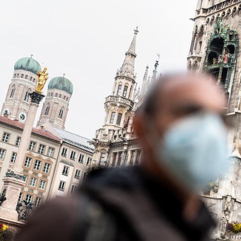 Bayern, München: Ein Mann mit Mundschutz geht über den Marienplatz