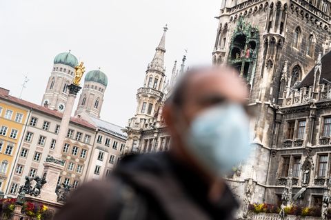 Bayern, München: Ein Mann mit Mundschutz geht über den Marienplatz