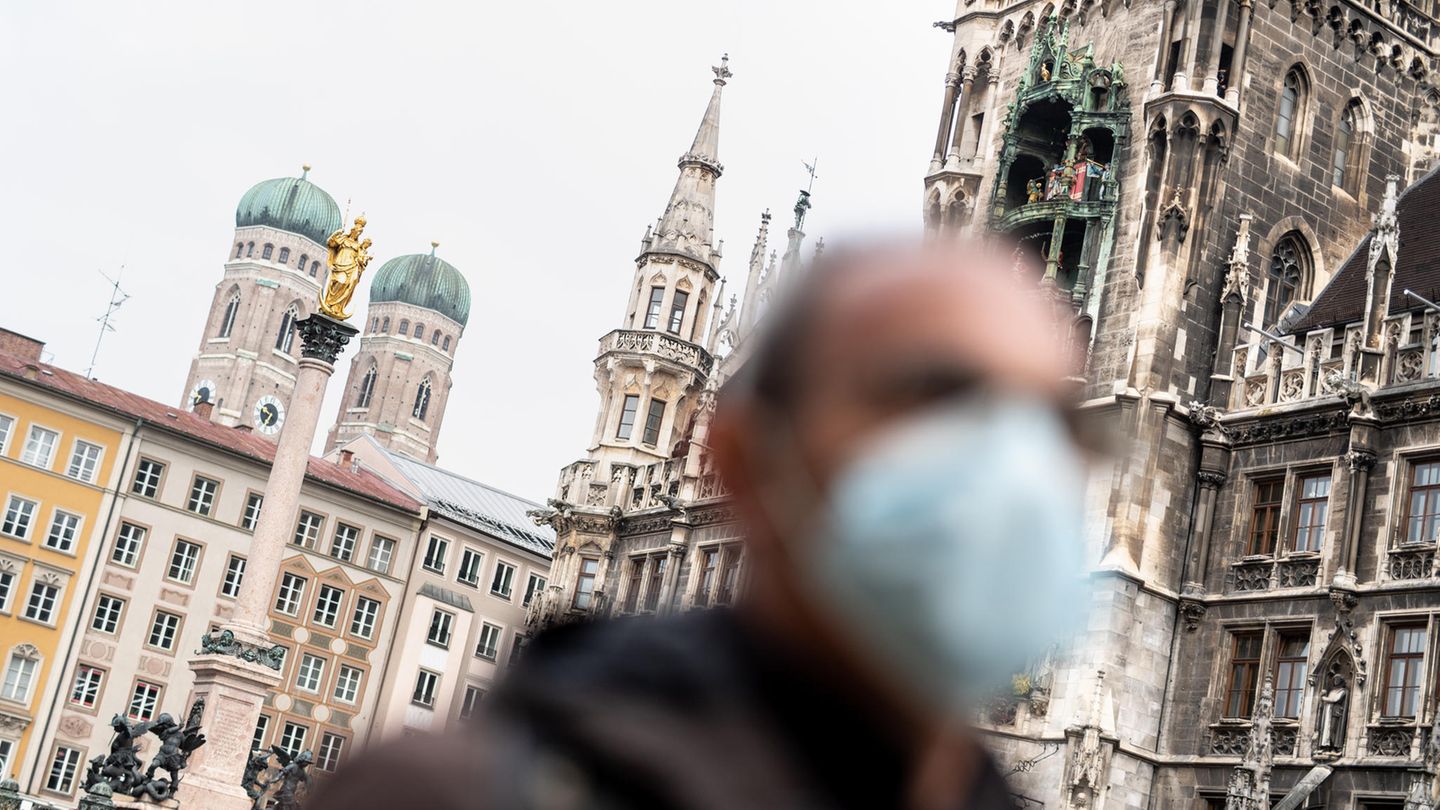Bayern, München: Ein Mann mit Mundschutz geht über den Marienplatz