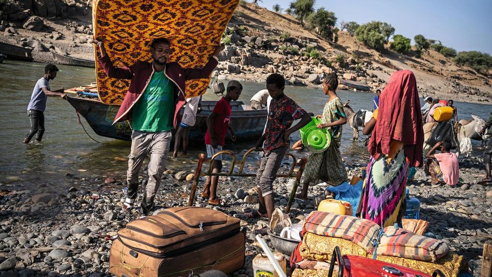 Setit river, separates Ethiopia from Sudan. Tigray people walk for days to reach this point. They fled a region in war against their Federal government. Boats brings a constant flow of newcomers who made their first step as refugee people. They bring wh... Erschöpft erreicht eine Familie die
sichere Seite des Grenzflusses im Sudan. Helfer
mit Eseln bieten
Trägerdienste an
