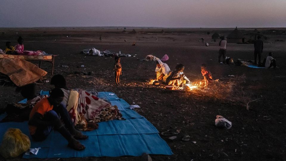 Hamdayet refugee camp, Sudan. Fire camp. Most of the big tent are full. A lot of people preferred to sleep outside. Before reaching Sudan, Ethiopians walked miles to escape the war in their Tigray region against their Federal Government.November 2020.... In der Abenddämmerung kocht eine Mutter. Bevor die UN-Hilfsmaschinerie anläuft, müssen viele im Freien schlafen