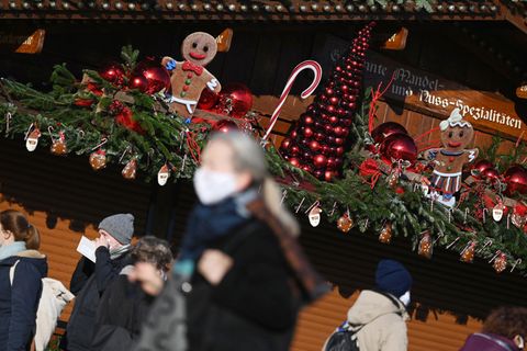 Coronavirus:  Passanten gehen an einem weihnachtlich geschmückten Stand in der Innenstadt vorbei