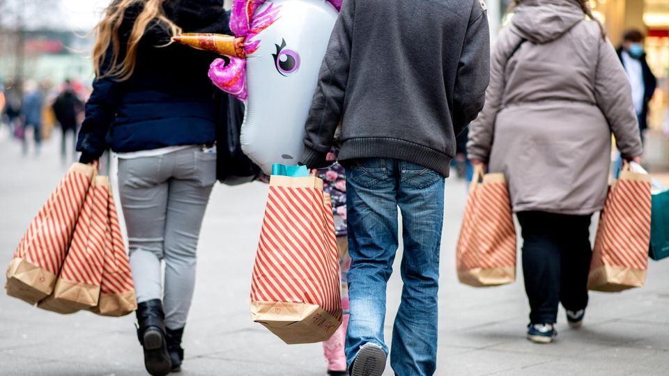 Menschen mit vollen Einkaufstüten gehen durch eine Fußgängerzone