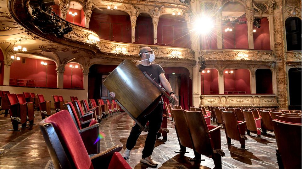 Ein Mitarbeiter trägt Stühle aus den Sitzreihen des Zuschauerraums des Berliner Ensembles