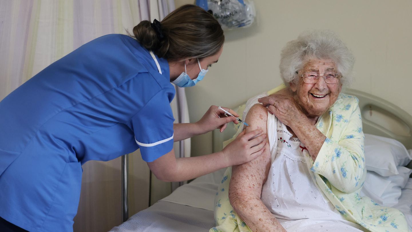 Ethel Jean Murdoch, eine 95-jährige Britin, sitzt auf ihrem Bett und erhält eine Corona-Impfung per Spritze