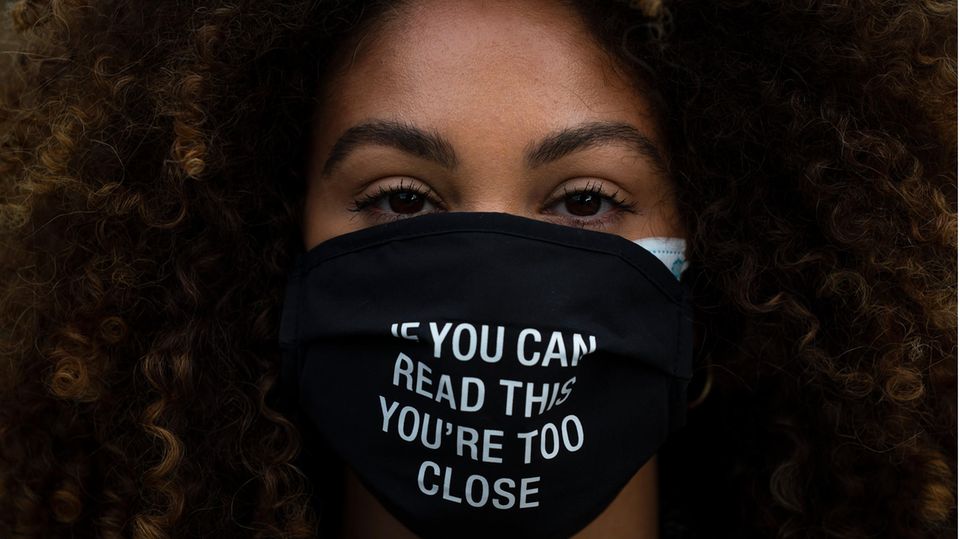 Frau trägt eine Schutzmaske mit der Aufschrift "If you can read this you're too close"