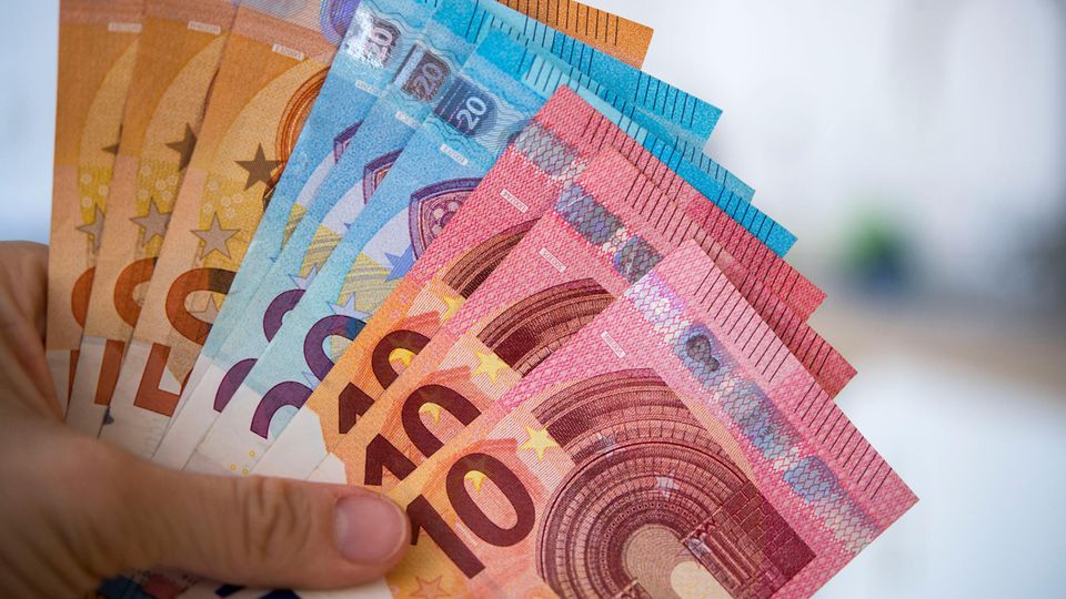 Kurzarbeit: Eine Frau hält Banknoten von 10, 20 und 50 Euro gefächert in der Hand