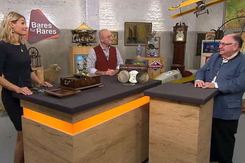 "Bares für Rares"-Expertin Bianca Berding, Moderator Horst Lichter und Verkäufer Jürgen Urbahn, der einen Christbaumständer dabei hat