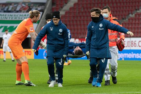 Schalkes Torwart Ralf Fährmann (l) beugt sich zu Mark Uth, der auf einer Trage verletzt vom Spielfeld getragen wird