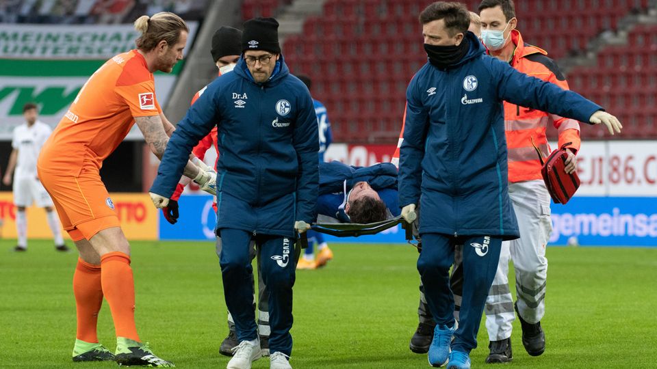 Schalkes Torwart Ralf Fährmann (l) beugt sich zu Mark Uth, der auf einer Trage verletzt vom Spielfeld getragen wird