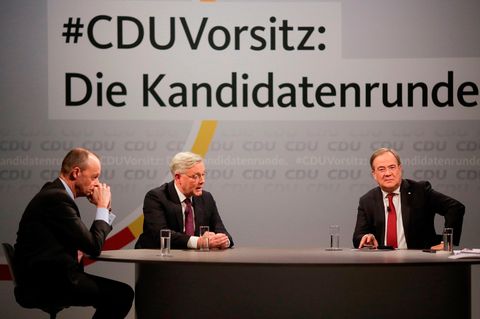 Unter dem Schriftzug "CDU-Vorsitz: Die Kandidatenrunde" sitzen drei Männer in Anzügen an einem ovalen Tisch