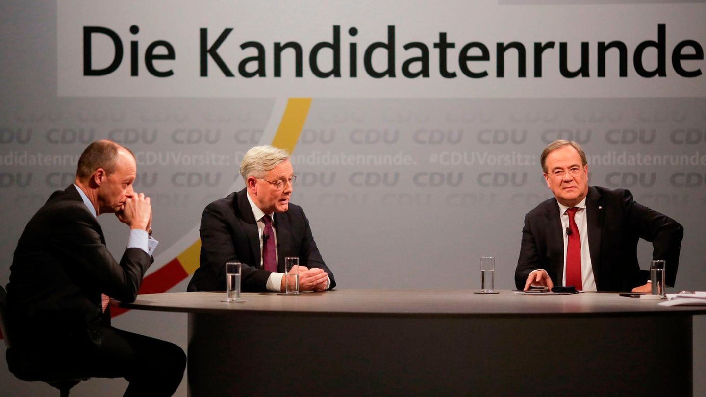 Unter dem Schriftzug "CDU-Vorsitz: Die Kandidatenrunde" sitzen drei Männer in Anzügen an einem ovalen Tisch