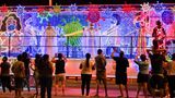 Cali: Weihnachtsfiguren mit Masken  Bewohner der Stadt Cali in Kolumbien betrachten die durch die Straßen rollenden Weihnachts-Trucks. Die Personen auf den Wagen und die Illumination berücksichtigen die Pandemie – Mund-Nasen-Schutz inklusive.