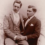 Dieses Bild könnte ein Hochzeitsfoto sein. Auch wenn der Blick des einen Mannes schüchtern nach unten geht, die Liebe der beiden zueinander ist unverkennbar.