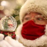 London: Ohne Mundschutz geht in diesem Jahr nichts  In einer Filiale des Kaufhauses Selfridges trägt dieser Weihnachtsmann einen Mund-Nasen-Schutz und hält eine Schneekugel in den Händen.