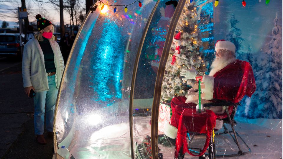 Bild 1 von 16 der Fotostrecke zum Klicken:  Social Distancing in Seattle   Mit Sicherheitsabstand in der Öffentlichkeit: Dieser Weihnachtsmann in Washington State plaudert mit einer Frau aus einer schützenden Plastikblase.