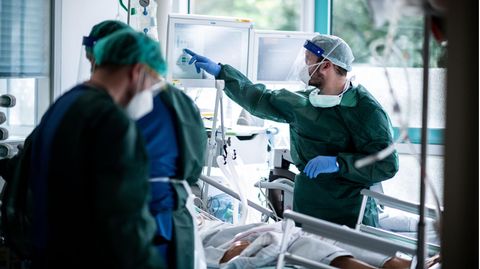 Mitarbeiter der Pflege in Schutzkleidung behandeln einen Patienten mit Corona-Infektion