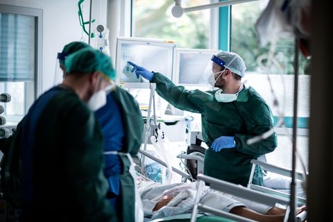 Mitarbeiter der Pflege in Schutzkleidung behandeln einen Patienten mit Corona-Infektion