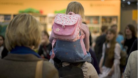 Ein Kind sitzt auf den Schultern seiner Mutter, die es durch ein sehr volles Geschäft trägt