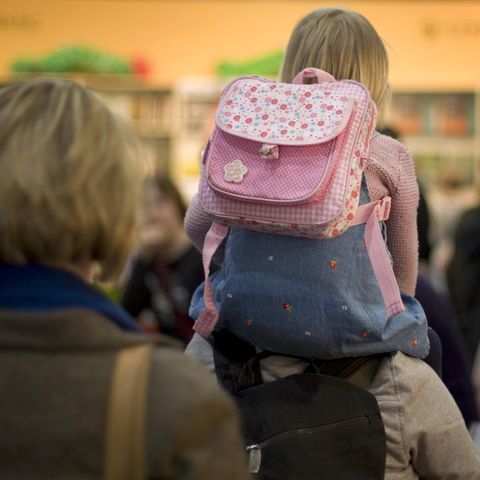 Ein Kind sitzt auf den Schultern seiner Mutter, die es durch ein sehr volles Geschäft trägt